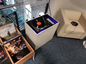 Vinylstation neben dem Trog mit den Schallplatten aus Güstrower Produktion und dem gemütlichen Sessel zum Anhören vor Ort.