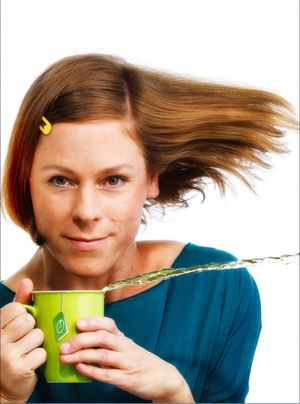 Inka Meyer, deren Haare scheinbar vom Wind verweht werden und die eine Tasse hält, aus der waagerecht Tee ausläuft; Foto (c) S. Büttner